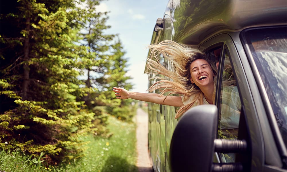 See the Country in an Rv but First Make Sure You Are Covered! - Blonde Woman on the Window of an Rv With Hands Out Smiling Enjoying Ride. Vacation Time